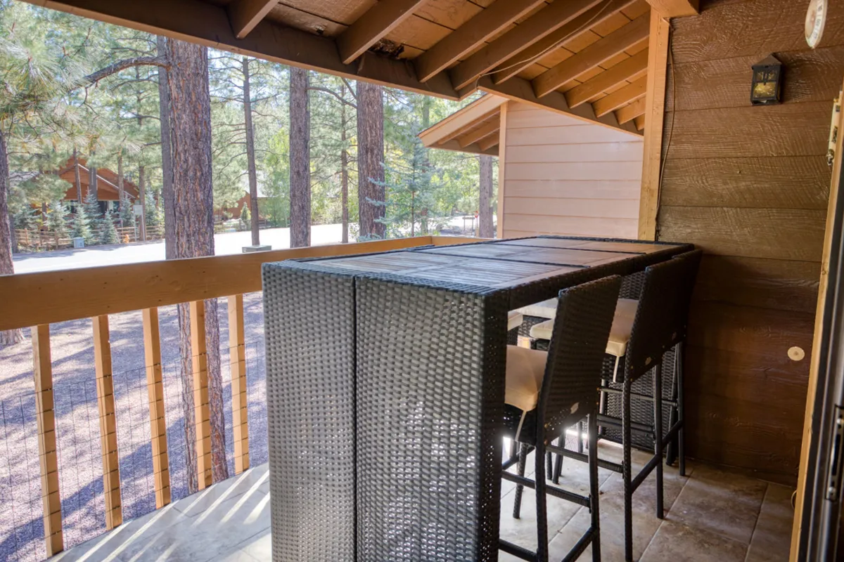 An open-concept living space featuring bar-style seating overlooking a tree-lined view, with wood accents and abundant daylight. The design emphasizes connectivity within the space, allowing for easy conversation and interaction between the kitchen and living areas.